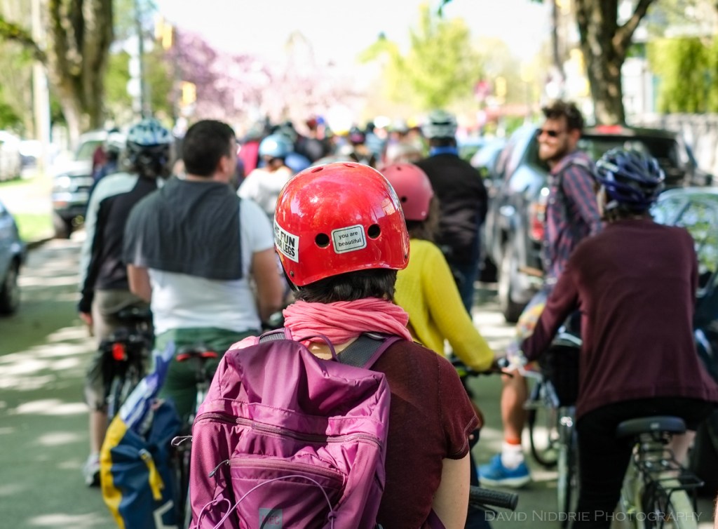 Cyclists ride beneath cherry and sakura blossoms in Vancouver.