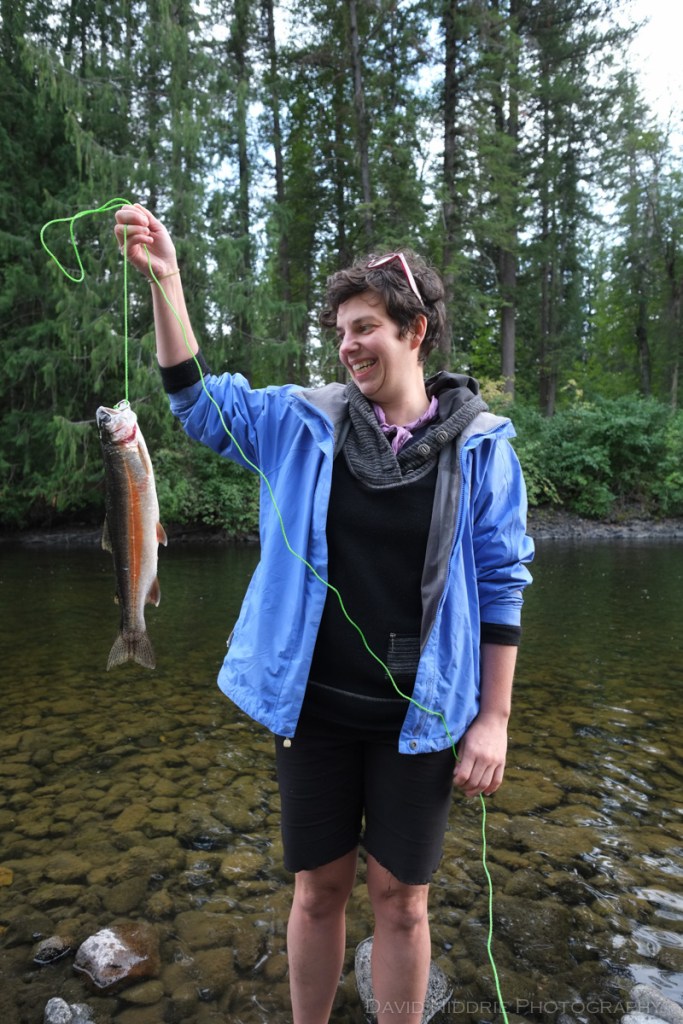 A woman displays her rainbow trout catch of the day while fishing in Wells Gray.