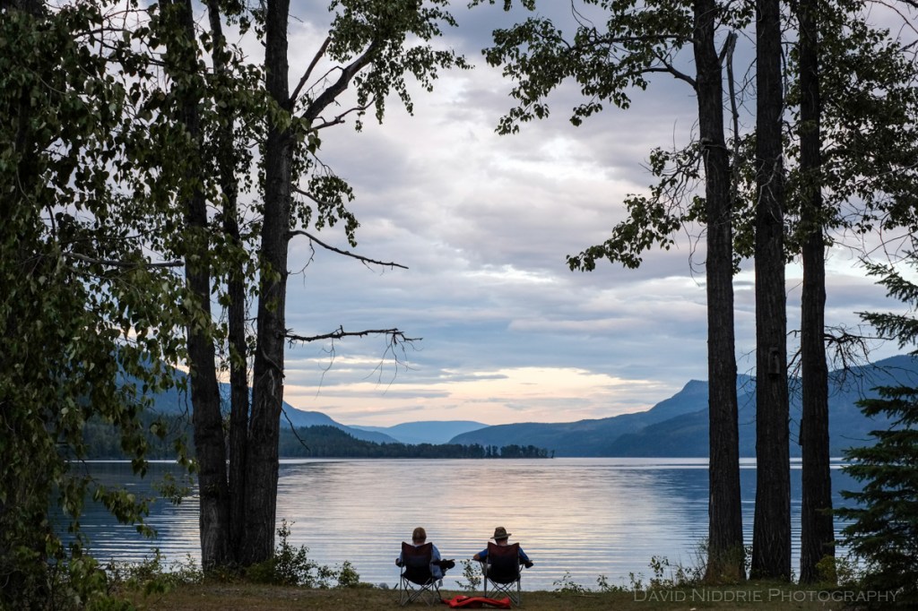 A couple reads beside Mahood Lake, Wells Gray Park, BC.