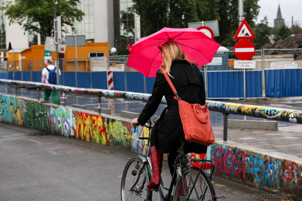 A woman covers up with an umbrella while cycling in the rain in Utrecht, Netherlands.