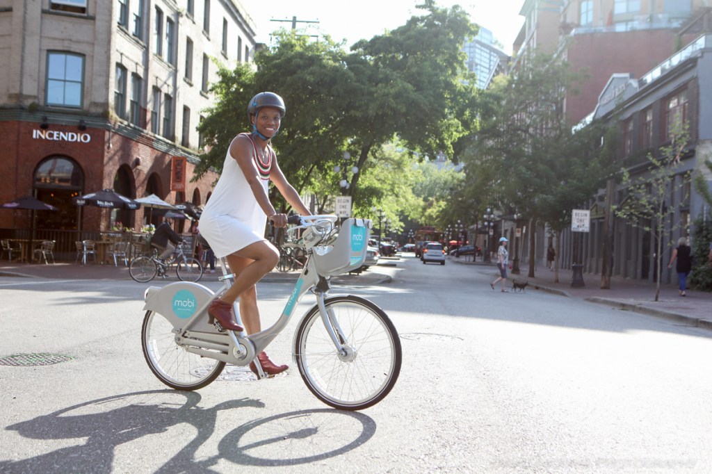 A woman rides through Gastown, Vancouver on a Mobi bike share bicycle