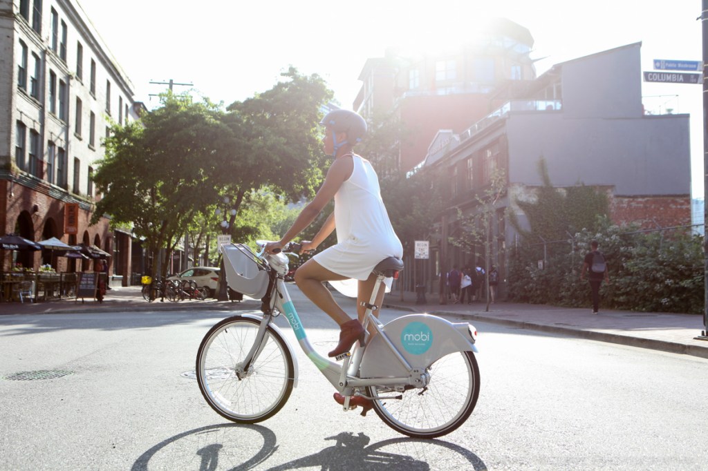 A woman rides through Gastown, Vancouver on a Mobi bike share bicycle