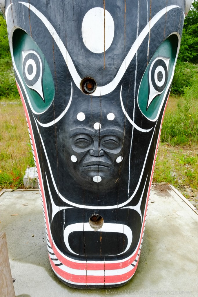 A figure peers from the base of a Totem Pole in Alert Bay, BC.
