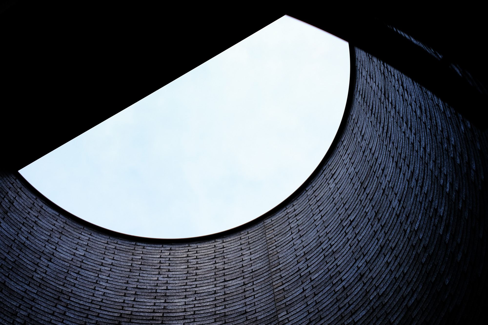 A look up from inside a sculpture of black brick and curved walls