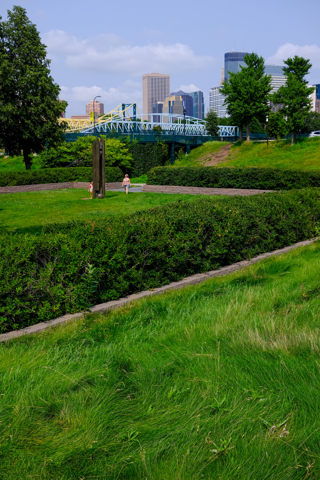 A woman and child walk amongst the lush grassland of the Sculpture garden.