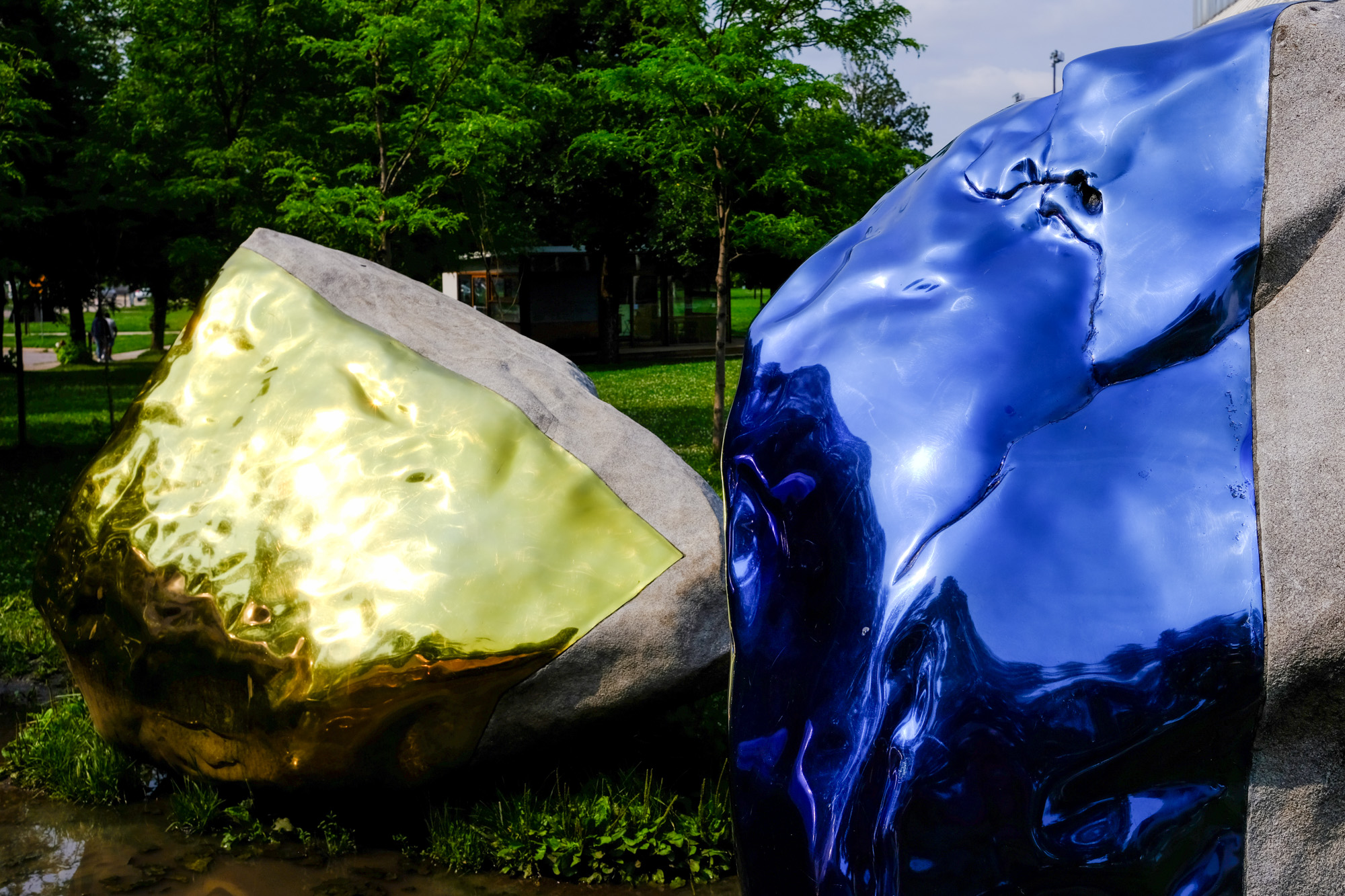 Rocks covered in metallic paint and metal contours glisten in the sunlight as blue and gold reflects.