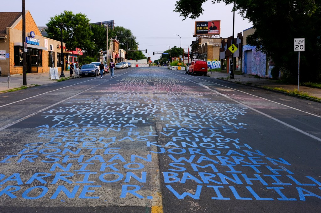 The street surrounding George Floyd Square in Minneapolis features the names of people killed by police written in block letters on the street.